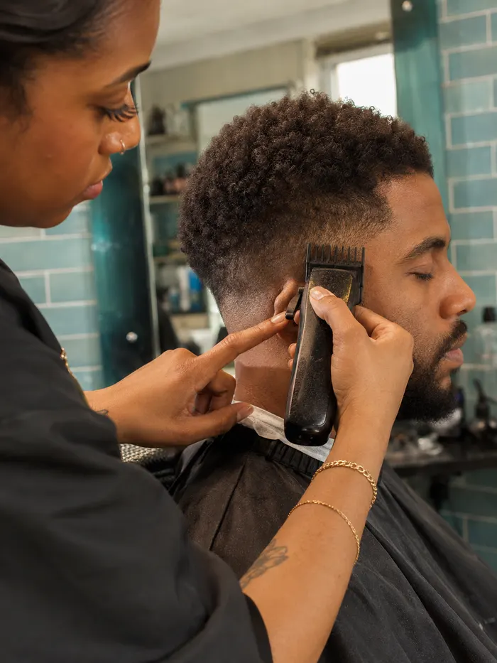 Barber using a guarded clipper to shape a textured cut